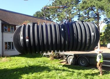 A sewage tank being lifted up a truck by a crane
